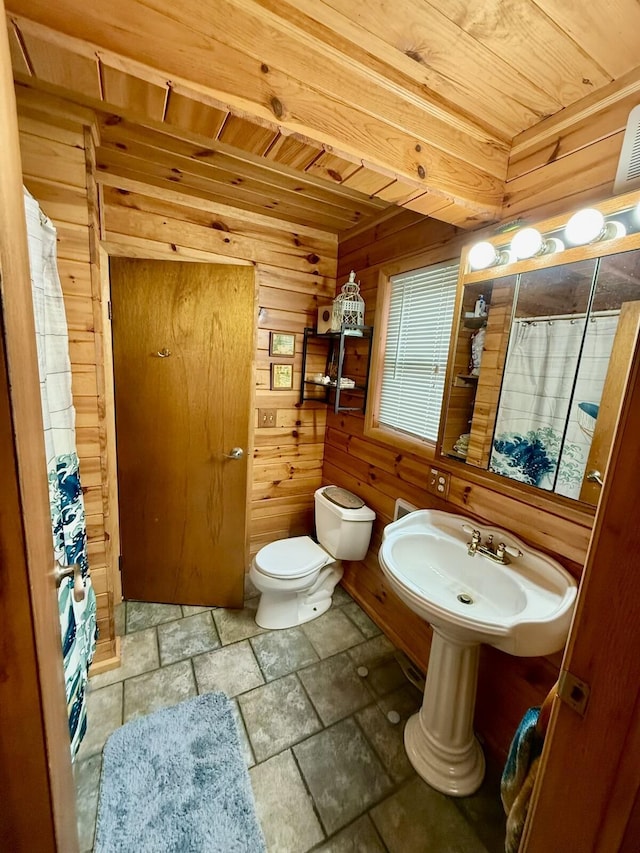 19110 Red Pine Dr, Hillman, MI 49746 - full bathroom featuring wooden ceiling, wooden walls, stone tile flooring, toilet, and curtained shower