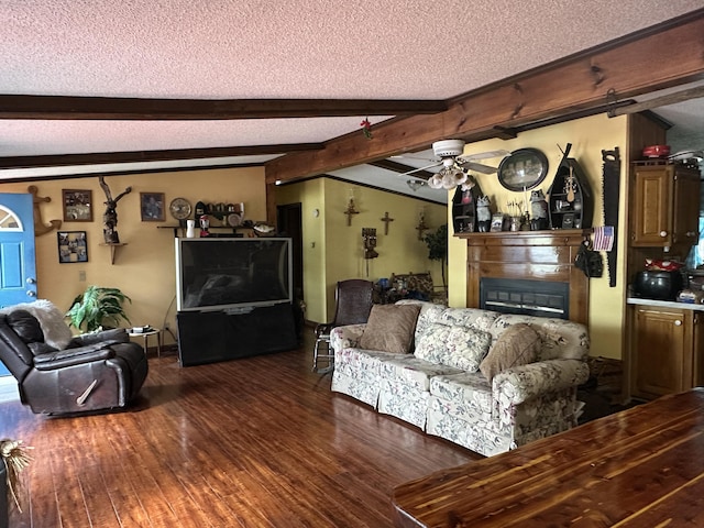 3469 Long Rapids Rd, Alpena, MI 49707 - living room with a textured ceiling, dark wood-style floors, a glass covered fireplace, beam ceiling, and a ceiling fan