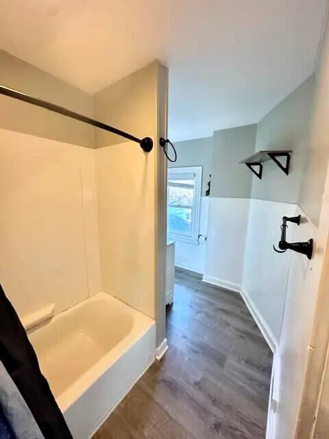 310 W Campbell St, Alpena, MI 49707 - bathroom featuring wood finished floors, bathing tub / shower combination, and baseboards