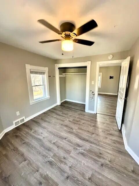 310 W Campbell St, Alpena, MI 49707 - unfurnished bedroom featuring wood finished floors, a closet, baseboards, and a ceiling fan