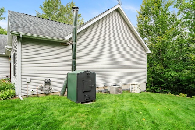 11882 Davis Creek Dr, Wolverine, MI 49799 - view of home's exterior featuring roof with shingles, a lawn, and central AC