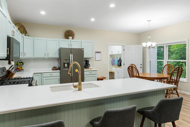 11882 Davis Creek Dr, Wolverine, MI 49799 - kitchen featuring a sink, stainless steel appliances, light wood-style flooring, a peninsula, and a chandelier