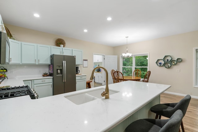 11882 Davis Creek Dr, Wolverine, MI 49799 - kitchen with stainless steel refrigerator with ice dispenser, a sink, light wood-style flooring, a chandelier, and a kitchen bar