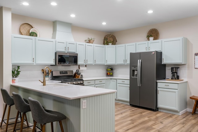 11882 Davis Creek Dr, Wolverine, MI 49799 - kitchen featuring stainless steel appliances, a peninsula, a kitchen bar, light wood finished floors, and light countertops