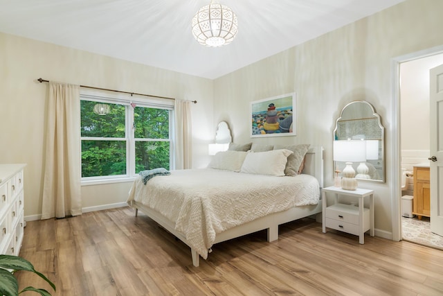 11882 Davis Creek Dr, Wolverine, MI 49799 - bedroom with light wood-style floors, a chandelier, baseboards, and ensuite bathroom