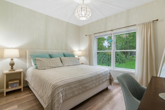 11882 Davis Creek Dr, Wolverine, MI 49799 - bedroom with a chandelier, wood finished floors, and baseboards
