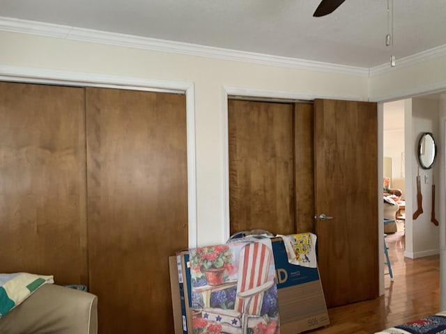 1253 N Partridge Point Rd, Alpena, MI 49707 - bedroom featuring ornamental molding, wood finished floors, two closets, and a ceiling fan