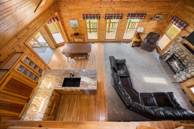 14250 Chippewa Trl, Johannesburg, MI 49751 - living room with wood walls, a fireplace, lofted ceiling, and carpet