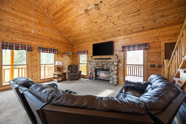 14250 Chippewa Trl, Johannesburg, MI 49751 - carpeted living room with wooden walls, a stone fireplace, high vaulted ceiling, rail lighting, and stairs