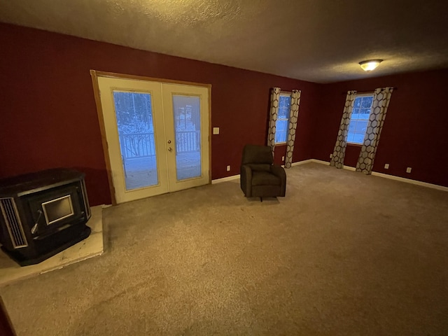 445 Noric Dr, Roscommon, MI 48653 - unfurnished room featuring a wood stove, french doors, carpet floors, baseboards, and a textured ceiling