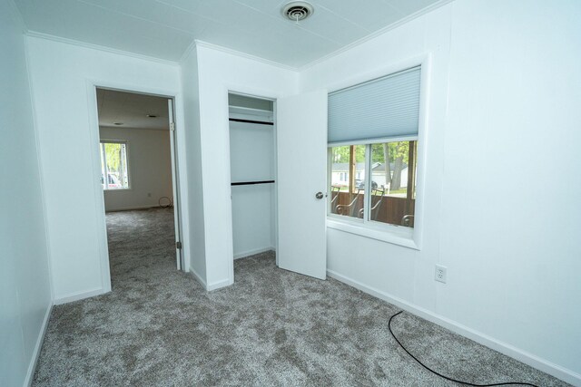 206 Harvey Ave, Houghton Lake, MI 48629 - unfurnished bedroom with carpet, ornamental molding, a closet, and baseboards