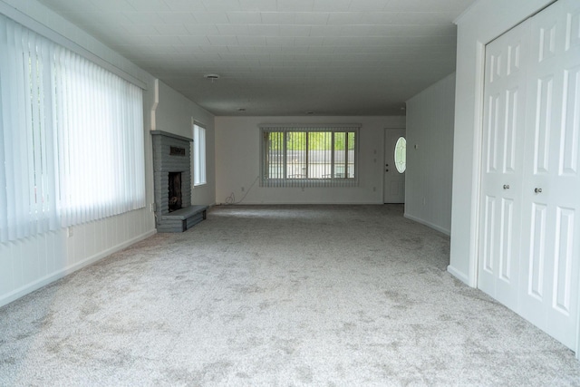 206 Harvey Ave, Houghton Lake, MI 48629 - unfurnished living room with carpet, a brick fireplace, and baseboards
