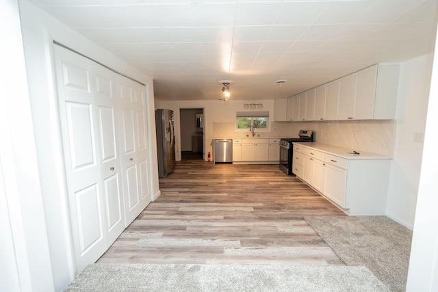 206 Harvey Ave, Houghton Lake, MI 48629 - kitchen with appliances with stainless steel finishes, white cabinets, light countertops, and light wood finished floors