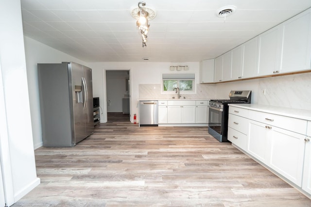 206 Harvey Ave, Houghton Lake, MI 48629 - kitchen with stainless steel appliances, white cabinets, light countertops, light wood-type flooring, and a sink