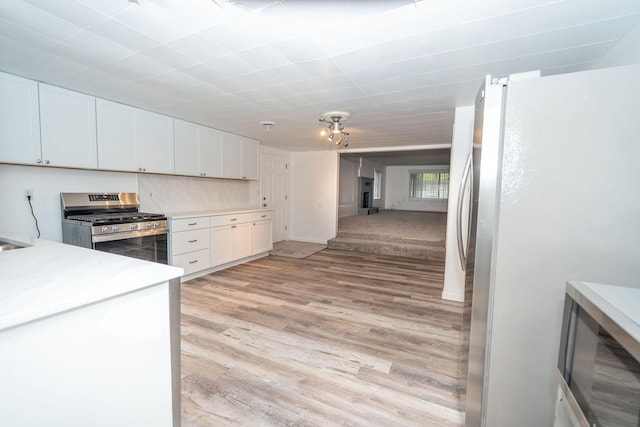 206 Harvey Ave, Houghton Lake, MI 48629 - kitchen featuring appliances with stainless steel finishes, light wood-style floors, white cabinetry, and light countertops