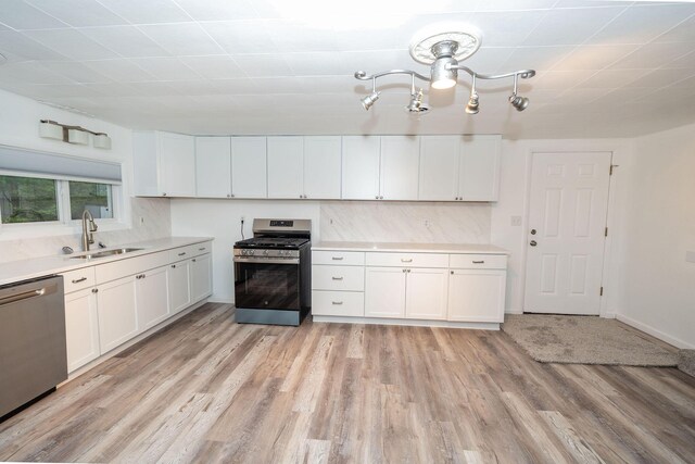 206 Harvey Ave, Houghton Lake, MI 48629 - kitchen featuring stainless steel appliances, a sink, light countertops, white cabinets, and light wood-style flooring