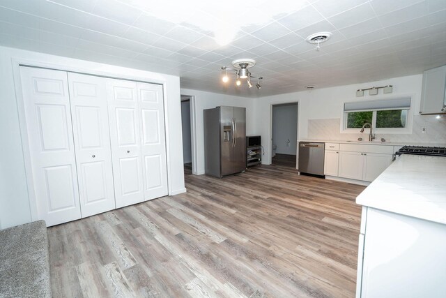 206 Harvey Ave, Houghton Lake, MI 48629 - kitchen with appliances with stainless steel finishes, a sink, light countertops, and light wood-style flooring