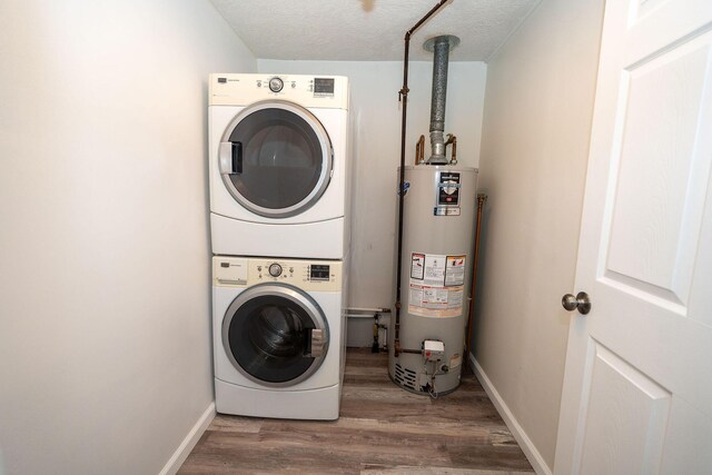 206 Harvey Ave, Houghton Lake, MI 48629 - washroom with stacked washing machine and dryer, water heater, wood finished floors, baseboards, and a textured ceiling