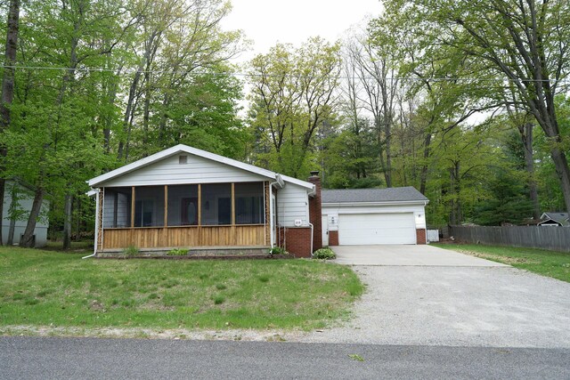 206 Harvey Ave, Houghton Lake, MI 48629 - view of front of property with brick siding, a sunroom, a garage, concrete driveway, and a chimney