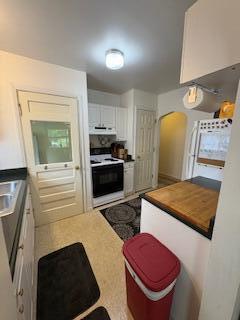 18598 Henry St, Melvindale, MI 48122 - kitchen featuring range with electric stovetop, ventilation hood, white cabinets, light countertops, and arched walkways