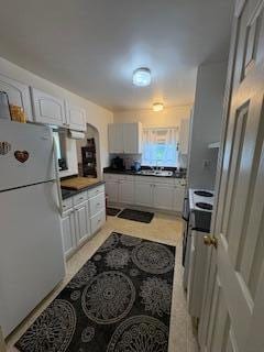 18598 Henry St, Melvindale, MI 48122 - kitchen with freestanding refrigerator, white cabinets, and dark countertops