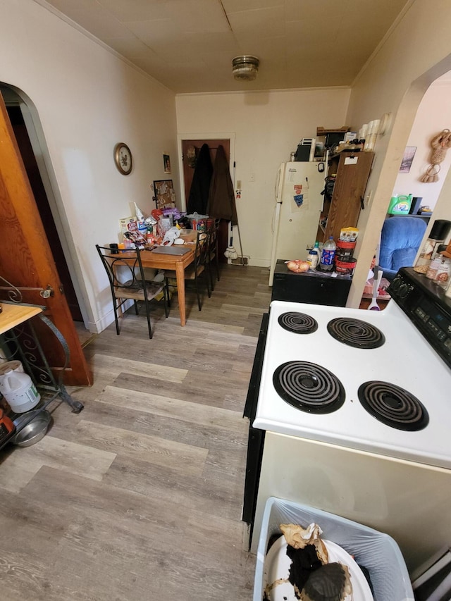 615 W Lake St, Alpena, MI 49707 - kitchen with arched walkways, white appliances, ornamental molding, and light wood-type flooring