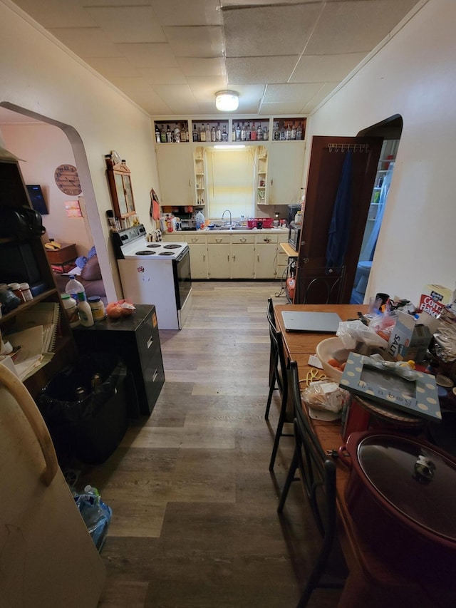 615 W Lake St, Alpena, MI 49707 - kitchen featuring white range with electric stovetop, arched walkways, light wood-style floors, open shelves, and a paneled ceiling