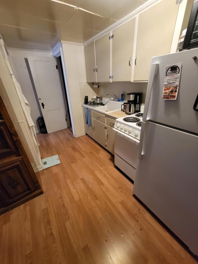 615 W Lake St, Alpena, MI 49707 - kitchen featuring white appliances, light wood-style flooring, a sink, light countertops, and white cabinets