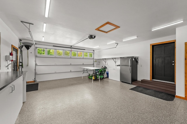 6801 Driftwood Cv, Saint Helen, MI 48656 - garage featuring freestanding refrigerator, a garage door opener, and refrigerator