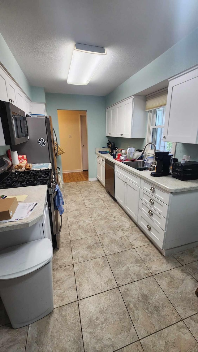 8619A Iowa St, Oscoda, MI 48750 - kitchen with stainless steel appliances, a sink, white cabinets, light countertops, and a textured ceiling