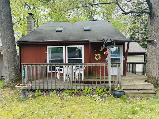 205 Beechwood Ave, Houghton Lake, MI 48629 - rear view of house with a deck, a chimney, a shingled roof, and a lawn