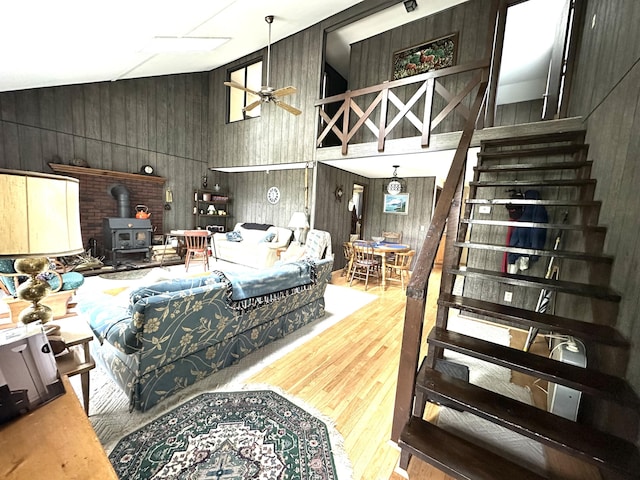 205 Beechwood Ave, Houghton Lake, MI 48629 - living area with a wood stove, stairway, wood walls, vaulted ceiling, and wood finished floors