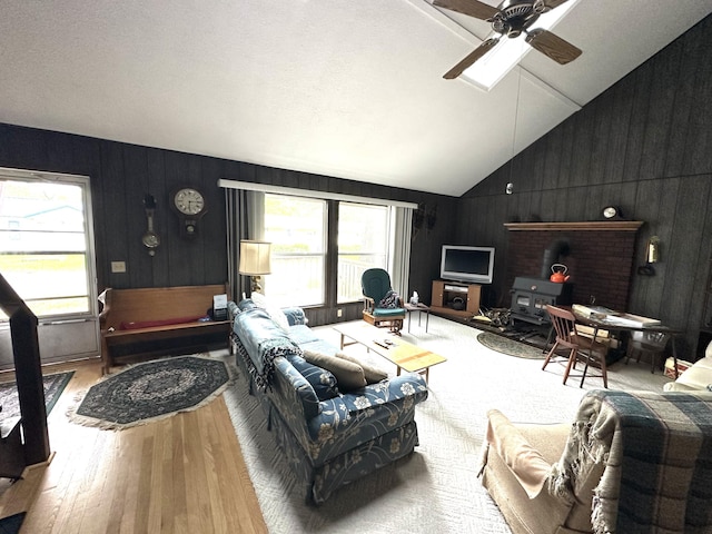 205 Beechwood Ave, Houghton Lake, MI 48629 - living area featuring hardwood / wood-style flooring, a wood stove, ceiling fan, lofted ceiling, and wood walls