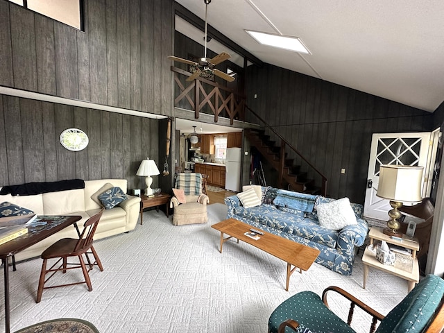 205 Beechwood Ave, Houghton Lake, MI 48629 - living area with wooden walls, carpet, stairs, high vaulted ceiling, and a ceiling fan