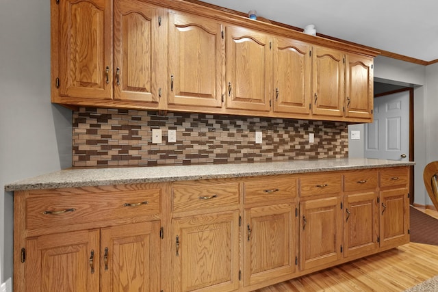 4285 Tower Hill Rd, Houghton Lake, MI 48629 - kitchen with tasteful backsplash, light wood-style flooring, light stone counters, and brown cabinets