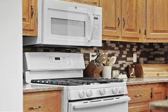4285 Tower Hill Rd, Houghton Lake, MI 48629 - kitchen featuring white appliances, tasteful backsplash, brown cabinets, and light stone countertops