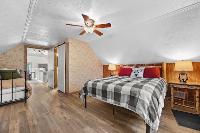 7028 Merrio Rd, Grayling, MI 49738 - bedroom with lofted ceiling, wood finished floors, a textured ceiling, baseboards, and a ceiling fan