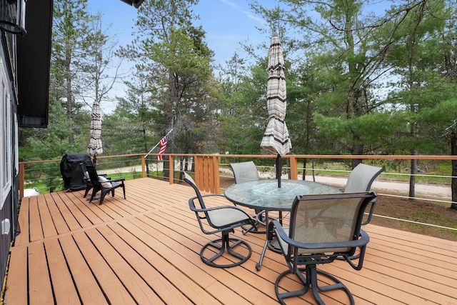 7028 Merrio Rd, Grayling, MI 49738 - wooden deck featuring outdoor dining space and view of wooded area