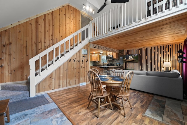 7028 Merrio Rd, Grayling, MI 49738 - dining space with wooden walls, stairway, ceiling fan, stone finish flooring, and lofted ceiling