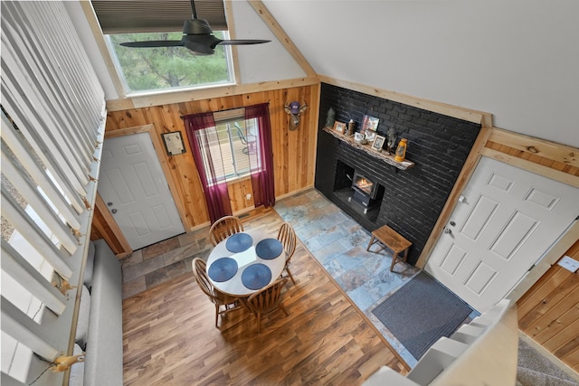 7028 Merrio Rd, Grayling, MI 49738 - living area featuring wood walls, a ceiling fan, a lit fireplace, light wood-type flooring, and baseboards