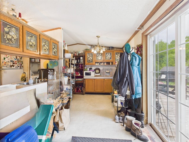 730 SE Cool Rd, Kalkaska, MI 49646 - kitchen featuring a chandelier, a textured ceiling, lofted ceiling, brown cabinets, and light carpet