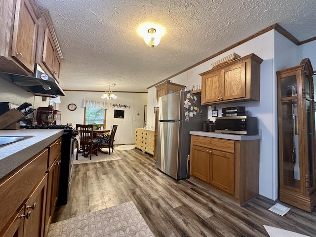 10162 Regimental Way, Grayling, MI 49738 - kitchen with appliances with stainless steel finishes, dark wood finished floors, crown molding, brown cabinetry, and a chandelier