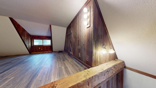 605 Cedar Ave, Houghton Lake, MI 48629 - stairway with wood finished floors, wooden walls, a textured ceiling, and a textured wall