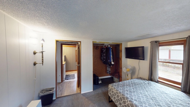 605 Cedar Ave, Houghton Lake, MI 48629 - bedroom featuring a textured ceiling, dark colored carpet, and baseboards
