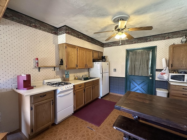 269 Dixson Dr, Grayling, MI 49738 - kitchen with white appliances, wallpapered walls, ceiling fan, light countertops, and brown cabinetry
