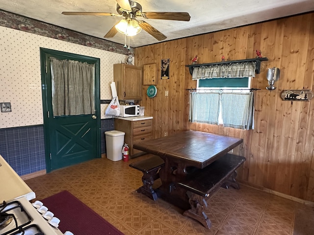 269 Dixson Dr, Grayling, MI 49738 - dining area with a ceiling fan, wood walls, wallpapered walls, and baseboards