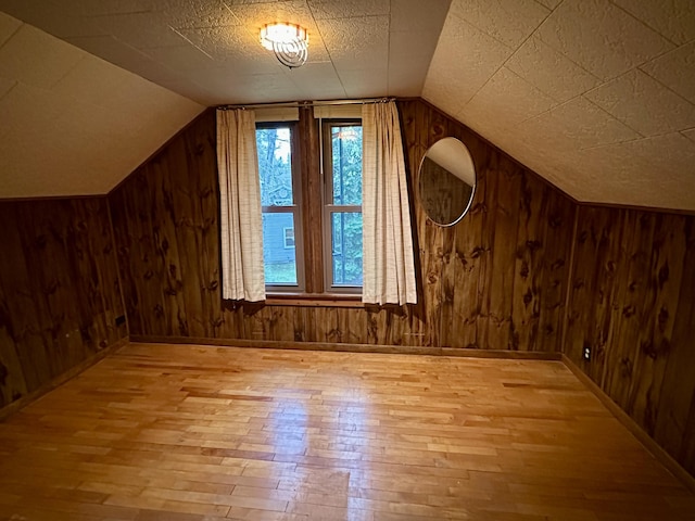 370 W Park Dr, Grayling, MI 49738 - additional living space with wood-type flooring, vaulted ceiling, wood walls, and baseboards