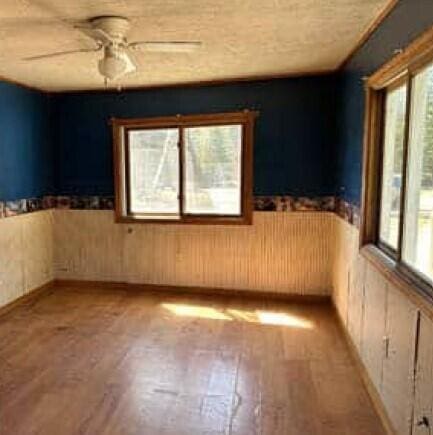 29098 W H 40, Moran, MI 49760 - empty room with a wainscoted wall, light wood finished floors, and ceiling fan