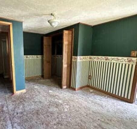 29098 W H 40, Moran, MI 49760 - spare room with a textured ceiling, radiator heating unit, and a wainscoted wall