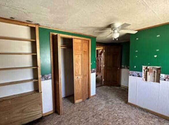 29098 W H 40, Moran, MI 49760 - unfurnished bedroom with a closet, a textured ceiling, and ceiling fan